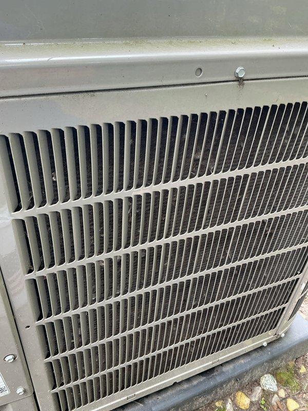 Completed annual HVAC maintenance on outdoor condensing unit. Inspected condenser coil assembly, which showed accumulation of dirt and debris between fins, and verified unit housing and protective components were intact and functioning properly. Unit operational with adequate airflow through finned coil structure.