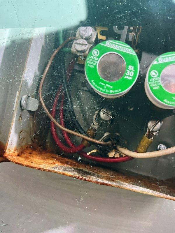 Responded to service call for non-operational A/C system with reported heating issue on 7-year-old basement unit. Upon inspection, discovered significant rust and corrosion on electrical component panel with compromised fuse holders and deteriorated wire connections, indicating moisture intrusion. Outdoor condenser unit exhibited heavily soiled coil fins with substantial dirt and debris accumulation restricting airflow. Documented electrical panel corrosion and condenser condition for recommended repairs including electrical component replacement and coil cleaning to restore proper system operation.