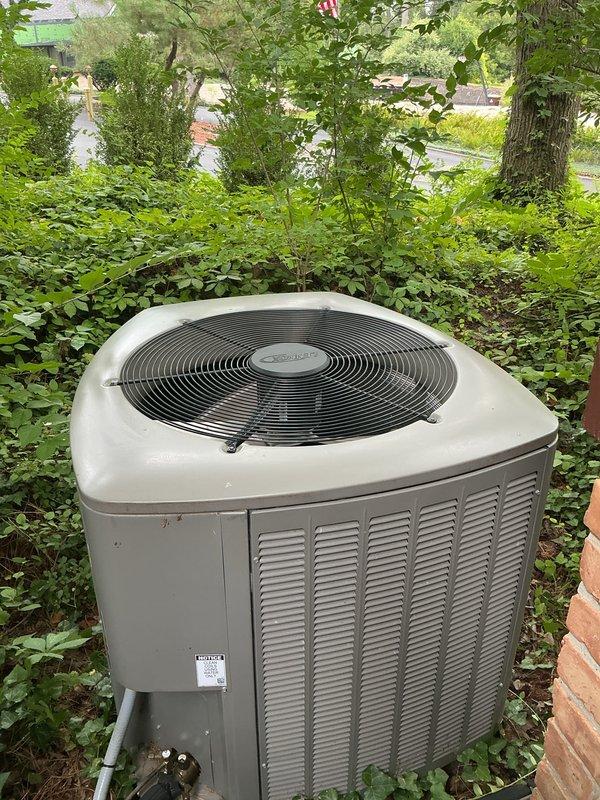 Completed annual preventative maintenance on residential split system air conditioning unit. Performed comprehensive inspection of outdoor condenser unit including visual assessment of cabinet condition, fan motor operation, and refrigerant line connections. Unit found operating within normal parameters with no immediate service concerns identified. Condenser positioned on hillside location with adequate clearance, though surrounding vegetation noted for monitoring. All components functioning properly at time of service.