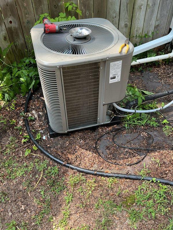 Completed annual heating and cooling maintenance on residential air conditioning condenser unit. Performed comprehensive system inspection including visual assessment of outdoor unit cabinet, fan assembly, and condenser coils. Documented heavy soiling and debris accumulation on heat exchanger fins with significant discoloration present, particularly on intake side of coil. Verified refrigerant line connections and insulation integrity on suction and liquid lines. Inspected condensate drain line routing and unit mounting on concrete pad. Unit operational at time of inspection with fan assembly functioning properly.