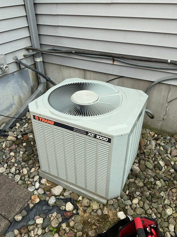 Responded to no cooling complaint on Trane XE 1000 air conditioning system. Upon arrival, verified outdoor condenser unit was receiving power and compressor was attempting to operate. Performed diagnostic evaluation of refrigerant system and discovered unit was operating with critically low refrigerant charge. Conducted leak detection inspection on refrigerant lines, coil connections, and condenser components. Located active refrigerant leak at service valve connection point on outdoor unit. Recovered remaining refrigerant from system per EPA regulations. Repaired leak at service valve, performed vacuum test to verify system integrity, and recharged system to manufacturer specifications. Verified proper amperage draw on compressor and condenser fan motor. Confirmed adequate airflow through condenser coil and checked temperature split across evaporator coil at indoor air handler. System restored to normal cooling operation with proper superheat and subcooling readings. Advised monitorin