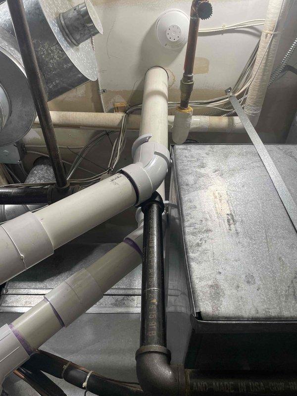 Completed installation of 5-ton air conditioning system with matching evaporator coil in front-positioned air handler unit. Installed condensate drainage system with PVC piping, including proper pitch and trap configuration, routing drain line to exterior discharge point. Reconnected all electrical connections, refrigerant lines, and ductwork to newly installed equipment, ensuring proper system operation and drainage function upon completion.