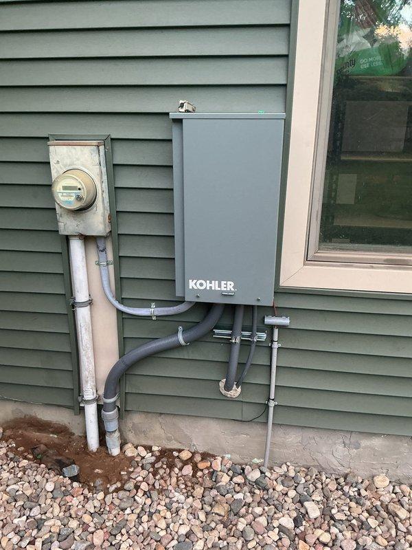 Successfully completed installation of a Kohler 20kW standby generator system at residential property. Installed generator unit on concrete pad with proper mounting and positioning adjacent to building exterior. Ran electrical conduit from generator to transfer switch mounted on exterior wall near existing 200-amp service and electric meter. Made all necessary electrical connections between generator, transfer switch, and main service panel using metallic and PVC conduit as required by code. Secured all conduit runs to building structure with appropriate clamps and supports. Installation performed in accordance with mechanical and electrical permits for generator, gas piping, and 200-amp service. Verified proper clearances, ventilation, and accessibility for maintenance. System tested and confirmed operational upon completion.