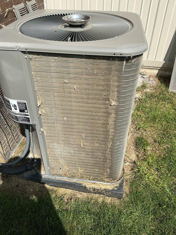Completed comprehensive ComfortGuard Maintenance on outdoor air conditioning condenser unit. Performed thorough inspection of system components including condenser coils, fan assembly, and electrical connections. Condenser coils exhibited heavy accumulation of dirt, dust, and environmental debris with significant discoloration and fin damage noted. Unit exterior showed substantial weathering with rust stains, paint deterioration, and corrosion on metal casing. Cleaned condenser fins to restore airflow efficiency and replaced air filter and evaporator pad as specified in maintenance package. Verified fan operation and protective grille guard integrity. Documented pre-existing cosmetic damage to unit panels and assessed overall system condition for continued operation.