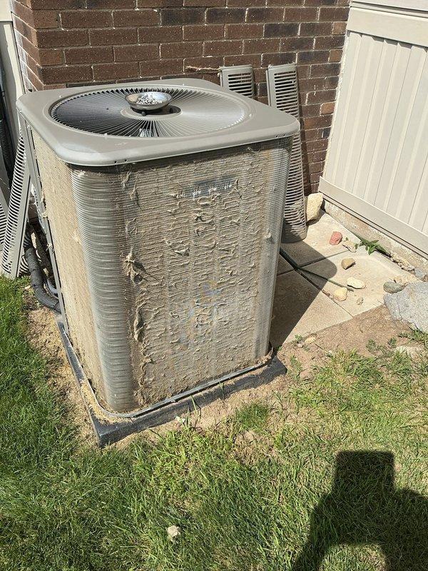 Completed comprehensive ComfortGuard Maintenance on outdoor air conditioning condenser unit. Performed thorough inspection of system components including condenser coils, fan assembly, and electrical connections. Condenser coils exhibited heavy accumulation of dirt, dust, and environmental debris with significant discoloration and fin damage noted. Unit exterior showed substantial weathering with rust stains, paint deterioration, and corrosion on metal casing. Cleaned condenser fins to restore airflow efficiency and replaced air filter and evaporator pad as specified in maintenance package. Verified fan operation and protective grille guard integrity. Documented pre-existing cosmetic damage to unit panels and assessed overall system condition for continued operation.