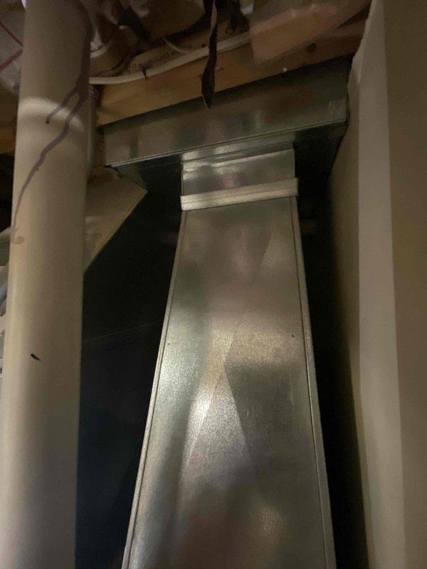 Conducted comprehensive assessment of dual HVAC system installation for residential property with two 16-year-old air conditioning units experiencing complete cooling failure and two gas furnaces of similar age, one non-operational. Following previous diagnostic service call confirming equipment replacement necessity, performed detailed evaluation of existing ductwork infrastructure, including galvanized steel rectangular supply ducts, return air grilles, and PVC condensate drainage systems. Inspected mechanical room installation showing proper integration of sheet metal ductwork with vertical and horizontal runs through floor joists in unfinished basement area. Documented current system configuration including vent locations, drainage piping with visible manufacturer markings, and structural duct mounting between wooden framing members. Prepared full system replacement estimate for dual zone HVAC installation requiring complete removal and replacement of both air conditioning condensi