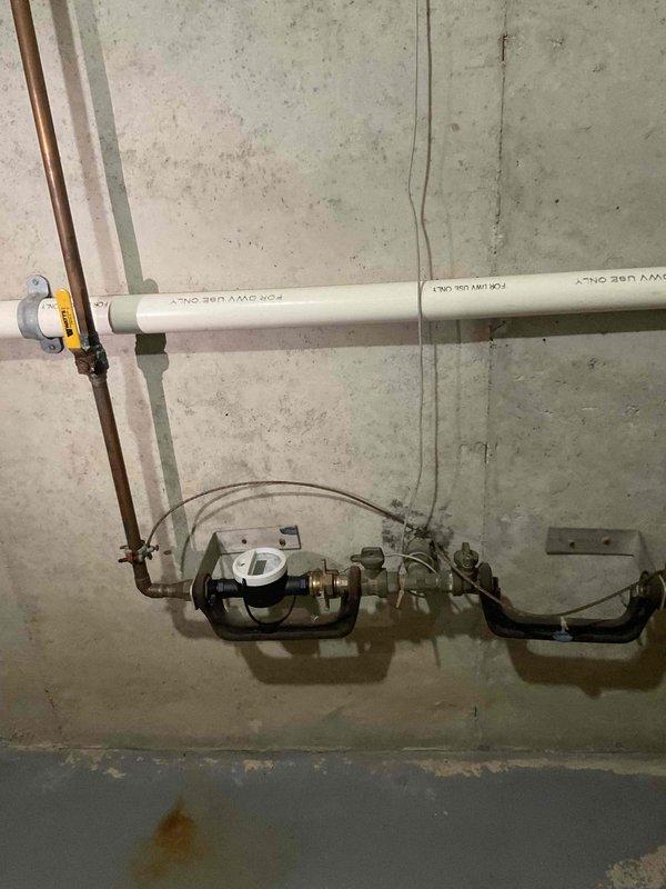 Conducted on-site assessment for standard water heater replacement in basement utility area. Existing natural draft water heater experiencing leak from bottom of tank, requiring full unit replacement. Evaluated existing plumbing configuration, venting system with metal flue pipe, and surrounding infrastructure including water meter, copper supply lines, and PVC drainage to provide comprehensive replacement estimate.