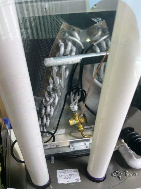 Returned to address frozen evaporator coil issue from recent furnace and 2-ton A/C installation. Previous technician found system iced over due to low refrigerant charge at startup. Added refrigerant to manufacturer specifications, verified proper system operation, and confirmed adequate airflow across coil. Also inspected and resolved condensate drainage leak from PVC piping connections. System now operating within normal parameters with no further issues detected.