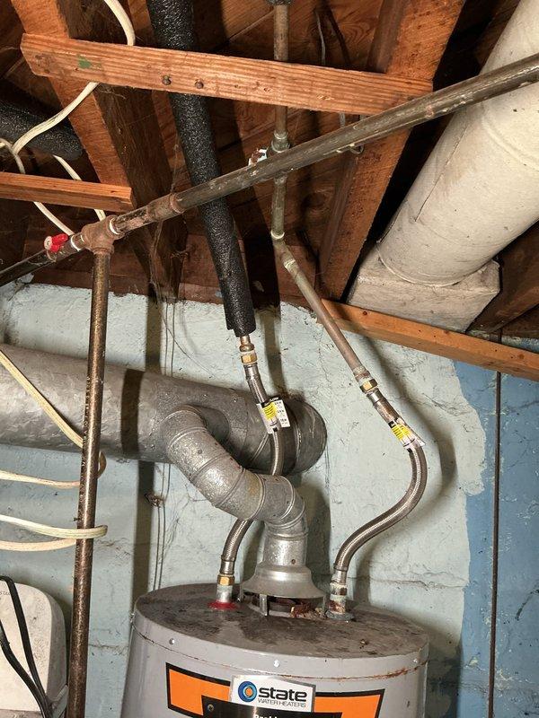 # Tanked Water Heater Service

Responded to service call for water heater system located in basement utility area. Upon arrival, conducted comprehensive inspection of State-brand tanked water heater unit and associated plumbing connections. Examined all copper supply lines, brass fittings, shutoff valves, and flexible connectors for proper operation and potential issues.

Inspected water heater tank exterior for signs of corrosion, leakage, or structural concerns. Verified proper venting configuration and clearances around unit. Tested all shutoff valves with red handles for proper function and accessibility. Examined compression fittings and connection points for signs of weeping or deterioration. Assessed condition of pipe insulation on vertical supply lines.

Documented existing system configuration including copper piping, brass valves, and flexible connectors. Photographed installation for service records, noting age-related discoloration on metal components and overall system con