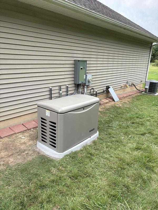 Completed installation of Kohler 20RCA standby generator and RXT-JFNC-150ASE automatic transfer switch at residential property. Generator unit was mounted on concrete pad with proper clearances, transfer switch panel installed in basement utility area, and electrical conduit routed along exterior siding to connect all components. System was wired, tested, and left fully operational for automatic backup power functionality.