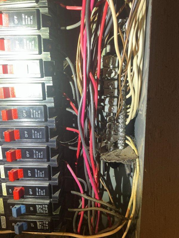 # Electrical Service - Whole Home Inspection

Performed comprehensive electrical inspection of 2-story freestanding condominium for recently purchased property. Conducted thorough evaluation of main electrical distribution panel, circuit breaker configuration, and overall system integrity.

## Primary Findings and Actions

Inspected main electrical panel box and documented existing conditions. Panel contains multiple circuit breakers with mixed configuration including standard black breakers, red switches, and blue toggle breakers. Identified two larger main disconnect switches or primary breakers at top of panel in gray/silver finish. Verified grounding bus bar connections on right side of panel with multiple wire terminations present.

Evaluated wiring organization and routing throughout panel interior. Observed numerous conductors including black, white, red, pink, beige/tan, and yellow insulated wires of various gauges entering and exiting panel box. Wiring extends from top of pane