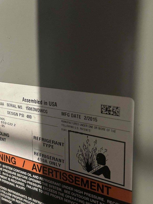 Performed diagnostic evaluation on 10-year-old residential air conditioning system with suspected refrigerant deficiency. Inspected outdoor condenser unit manufactured in February 2015, confirmed R-410A refrigerant type per manufacturer specifications. Documented equipment condition and serial number 15063WDWCG for service records.