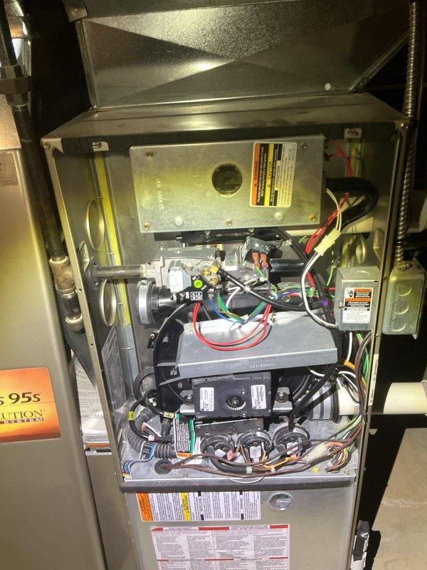 Completed comprehensive furnace cleaning and inspection tune-up on residential heating system. Accessed furnace cabinet, inspected blower motor assembly, electrical connections, control boards, and all internal components. Verified proper operation of all mechanical systems, checked wiring integrity across multiple colored wire connections, and confirmed all safety labels and manufacturer specifications were intact and visible.