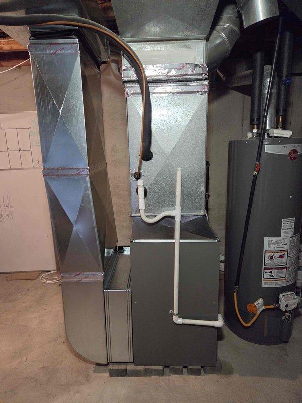 Completed installation of 90,000 BTU furnace unit in basement mechanical room. Installed new furnace with proper venting using white PVC piping, connected galvanized metal supply plenum and ductwork, and established all necessary gas line connections. Reconnected existing electrical service, verified all safety controls, and ensured proper clearances from water heater and surrounding utilities per code requirements.