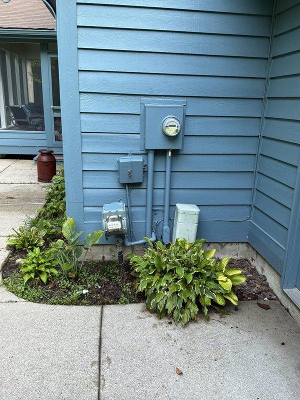 Conducted comprehensive site assessment for backup generator installation at 3,700 square foot colonial residence requiring updated estimate from previous 2022 evaluation. Evaluated existing electrical service entrance equipment, including main meter base, electrical panel, and associated conduit routing on exterior wall to determine optimal integration point for automatic transfer switch and generator connection. Documented current electrical panel configuration with dual columns of circuit breakers to assess load requirements and determine appropriate generator sizing for whole-house or critical circuits backup power solution. Photographed existing utility infrastructure and service entrance components to provide accurate specifications for generator system design and installation planning.