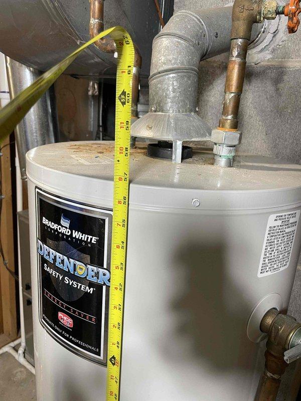 Conducted water heater estimate at single-family residence with non-functional existing unit requiring urgent replacement. Assessed current Bradford White Defender Safety System water heater installation, documented unit dimensions and existing plumbing configuration including copper supply lines with brass fittings, galvanized flue venting system, and PVC exhaust penetration through concrete block foundation wall. Provided replacement options and installation specifications for expedited service.