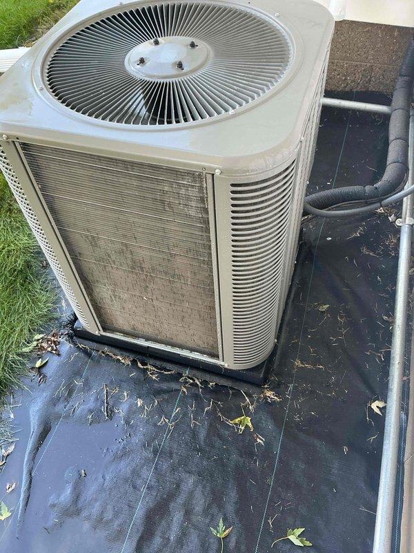 Completed air conditioning maintenance and tune-up on residential split system outdoor condenser unit. System had previously received furnace maintenance; this visit focused on the cooling equipment inspection and seasonal preparation. Performed comprehensive evaluation of condenser unit including visual inspection, cleaning of debris from surrounding area, assessment of coil condition, and verification of proper operation. Unit found to be functioning properly with no issues identified. Documented equipment condition with photographs showing outdoor condenser placement on protective pad with some accumulated debris and dirt on exterior panels, consistent with normal outdoor exposure for a system approximately two years old.