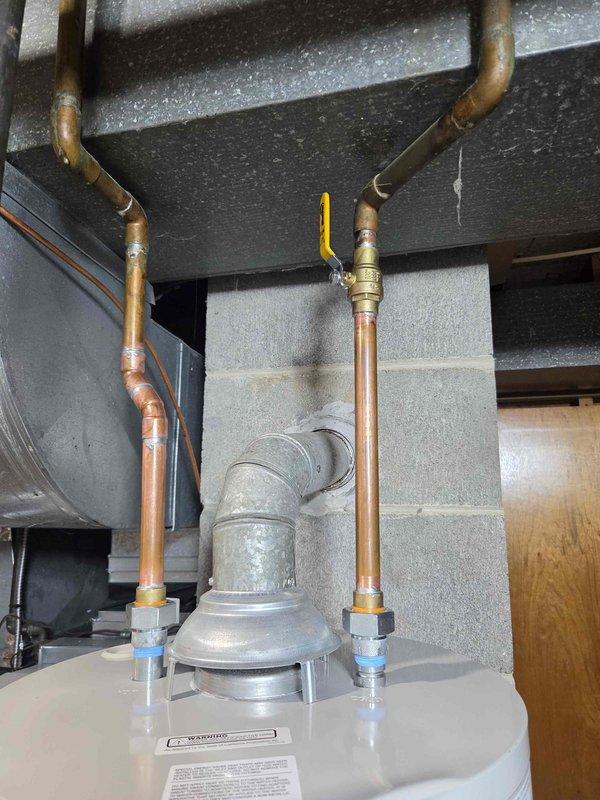 Completed installation of new tanked water heater in basement utility area. Connected hot and cold water supply lines using copper piping with brass compression fittings, installed galvanized vent flue system, and verified all connections for proper operation and code compliance.