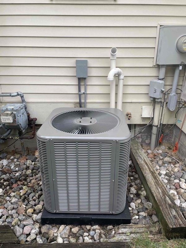 Completed installation of 2.5-ton Lennox air conditioning condenser unit with matching evaporator coil in left side yard location. Unit was positioned on rubber pad over wooden platform base in landscaped rock bed area, with all refrigerant lines, electrical conduit, and PVC drainage properly connected to existing residential electrical service and routed along exterior wall. System was successfully reconnected, tested, and verified operational per manufacturer specifications.