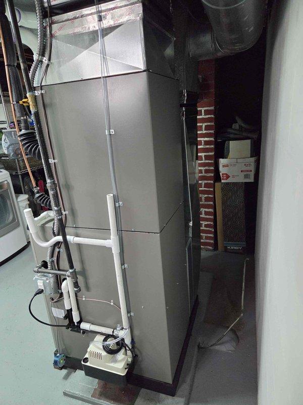 Completed full HVAC system installation including new furnace and air conditioning unit in basement utility area. Installed gray metal furnace with proper ductwork connections, integrated condensate drainage system using white PVC piping, and mounted new air filter assembly. System was tested for proper operation, and customer qualified for available utility rebates from Semco and Consumers Energy upon completion.