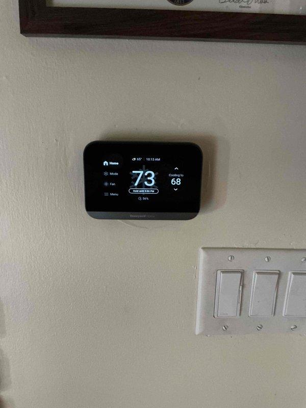 Responded to service call for air conditioning system providing insufficient cooling. Upon arrival, verified thermostat was set to 68°F with current indoor temperature reading 73°F, indicating a 5-degree temperature differential. Performed visual inspection of outdoor condenser unit located on exterior concrete pad. Unit appeared to be approximately 4 years old with no visible signs of physical damage or refrigerant leakage. Condenser coils showed normal wear consistent with age, and fan grille was intact and operational. Electrical connections and conduit appeared secure with no exposed wiring. System evaluated for potential issues affecting cooling capacity including airflow restrictions, refrigerant levels, and component functionality. Customer expressed interest in replacing furnace equipment located in basement. Documented current system conditions through photographic records of both thermostat display and outdoor condenser unit for reference.