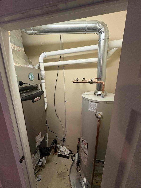 Completed full HVAC system installation including Lennox furnace (70,000 BTU capacity), 1.5-ton air conditioning unit with matching evaporator coil, and humidifier in residential utility closet. Installation included new electrical circuit for equipment, PVC venting for high-efficiency furnace routed through exterior wall, metallic ductwork modifications with 90-degree transitions to accommodate equipment layout, and copper refrigerant line set connecting outdoor condensing unit to indoor coil. All equipment properly positioned alongside existing water heater in confined mechanical space, with appropriate clearances maintained for service access. Permits obtained for mechanical and electrical work prior to installation, and all components installed per manufacturer specifications and local code requirements.