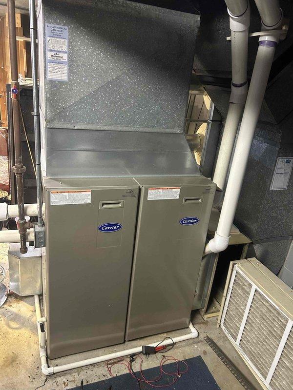 Performed comprehensive AC tune-up on residential split system with outdoor condenser unit and Carrier indoor air handler/furnace combination. Inspected outdoor condenser unit showing age-related weathering and dirt accumulation; cleaned unit exterior and verified fan operation through protective guard. Evaluated indoor evaporator coil mounted above furnace, noting visible condensation indicating active cooling cycle. Checked refrigerant levels and system pressures to determine if refrigerant charge was adequate; found system operating within manufacturer specifications with no refrigerant leak detected or addition required. Verified proper condensate drainage through PVC drain lines, inspected electrical connections, and confirmed system cycling properly. All components functioning as designed with no immediate service needs identified beyond routine maintenance completed.