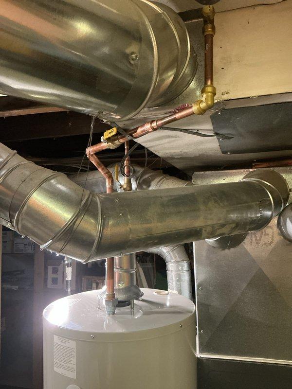Successfully installed a new 40-gallon tanked water heater (model RG240T6N) in the basement utility area. The installation included proper connections to existing copper supply lines with brass fittings, integration with the HVAC ductwork system, and all necessary plumbing connections to ensure optimal performance and code compliance.