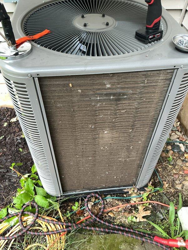 Performed scheduled preventive maintenance on outdoor air conditioning condenser unit. Cleaned heavily soiled front panel and coil surfaces, removing significant accumulation of dirt, debris, and organic matter that had restricted airflow. Verified system operation with digital multimeter, recording temperature reading of 93°F. Removed vegetation and debris from base of unit to ensure proper drainage and airflow clearance around equipment.