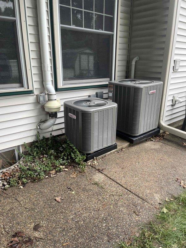 Completed full HVAC system installation including two furnaces (90,000 BTU and 45,000 BTU units), two air conditioning condensers (3-ton and 1.5-ton units), humidifier, and liner with all necessary reconnections. Both outdoor condenser units were positioned on concrete pads against the building exterior with proper drainage lines installed, and all refrigerant lines and electrical connections were completed per mechanical permit specifications.