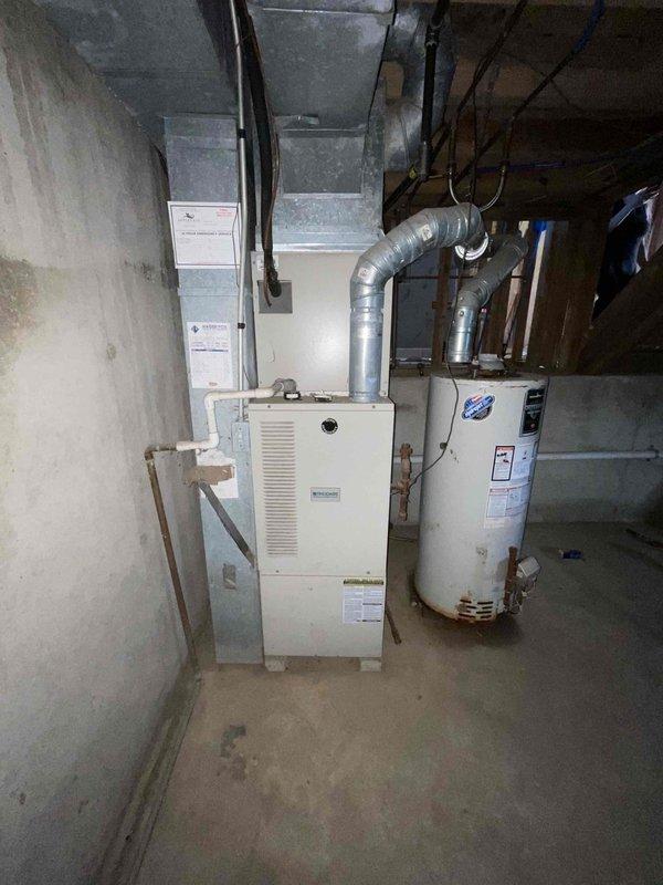 Completed full system estimate for residential HVAC replacement involving 16-year-old air conditioning unit and furnace located in basement utility area. Assessed existing white furnace with overhead ductwork distribution system and exterior condensing unit, documented current system configuration including electrical service connection at exterior meter location, and photographed equipment conditions to provide comprehensive replacement quote for complete heating and cooling system.