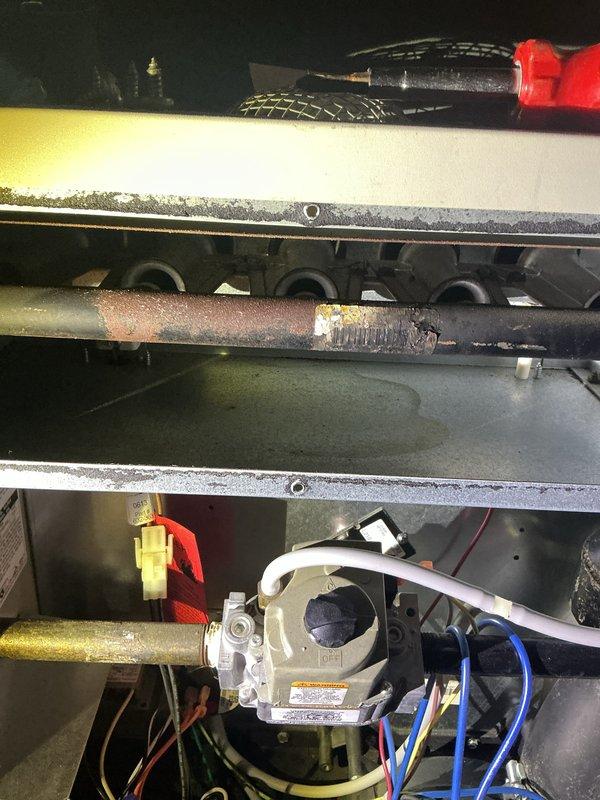 Completed annual heating maintenance inspection on residential HVAC system. Accessed unit interior and performed comprehensive visual inspection of all components. Examined electrical connections, wiring bundles, and control systems - all connections found secure with proper color coding intact. Inspected gas valve assembly and associated safety controls for proper operation. 

During inspection, identified significant corrosion and deterioration on copper refrigerant line, with heavy rust formation and surface degradation noted along horizontal run through unit compartment. Documented condition with photographs for maintenance records. Verified condensate drain line routing and condition. Assessed overall unit cleanliness, noting dust accumulation on interior surfaces consistent with normal operation. All mechanical components accessible during inspection appeared functional, though copper line corrosion will require monitoring or replacement to prevent future refrigerant leaks.