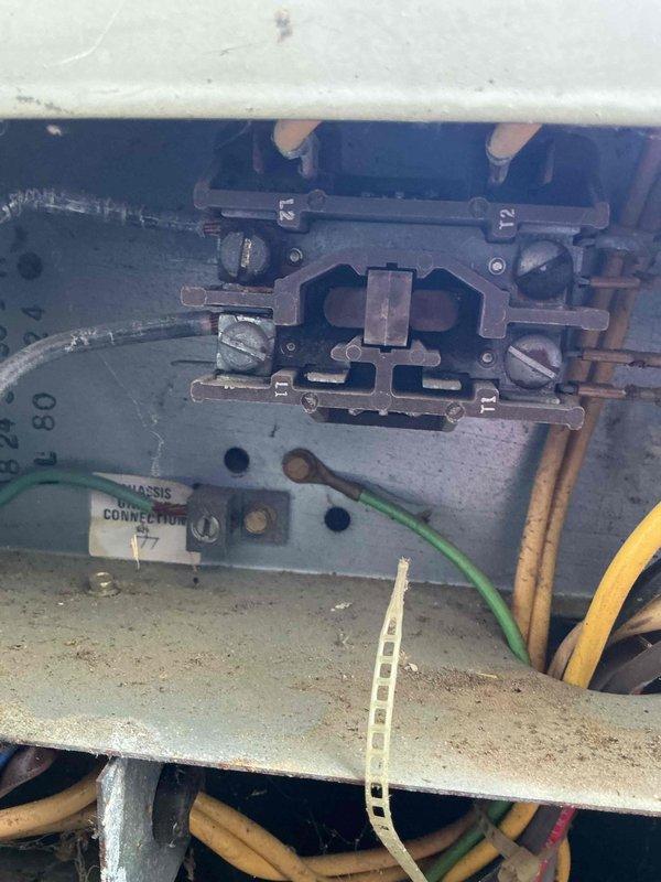 Responded to no cooling complaint on 15-year-old residential air conditioning system. Upon arrival, performed visual inspection of outdoor condensing unit and electrical connections. Documented existing equipment condition including outdoor unit placement, electrical meter configuration, and control panel wiring. System showed signs of age-related wear with weathering evident on unit exterior. Inspected electrical terminal connections, chassis grounding points, and wire routing within control panel. Photographed equipment for service records showing terminal block configuration numbered for circuit identification and multi-conductor wiring connections in various colors. Assessed outdoor unit positioning against building structure with adequate clearance for airflow. Noted standard residential installation with conduit routing from meter to equipment. Equipment accessible for service with no obstructions preventing maintenance access.