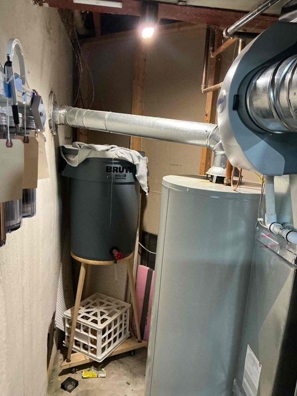 Responded to callback for hot water heater leak following previous day's HVAC installation. Inspected 110K BTU furnace and 3.5 ton A/C system with coil installation. Upon arrival, identified significant rust corrosion and water leakage at base of water heater unit, with moisture damage visible on concrete floor and ventilation grill showing extensive rust staining. Documented equipment condition with photos showing compromised water heater integrity and newly installed HVAC system components including flexible ductwork connections. Determined water heater failure unrelated to recent furnace and air conditioning installation work.