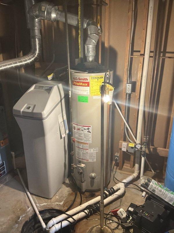 Conducted on-site evaluation for water heater replacement in residential basement utility area. Customer requested estimate for both tankless and standard tank water heater options as new installation to replace existing natural draft unit. Assessed current A.O. Smith ProMax conventional water heater, existing plumbing configuration including copper and PEX supply lines, venting requirements, and available space for potential tankless installation. Documented mechanical room layout, proximity to water softener system, electrical panel access, and ceiling clearances for proper venting options. Provided comprehensive estimate covering equipment specifications, installation requirements, and necessary modifications for both natural draft tank and tankless water heater systems.