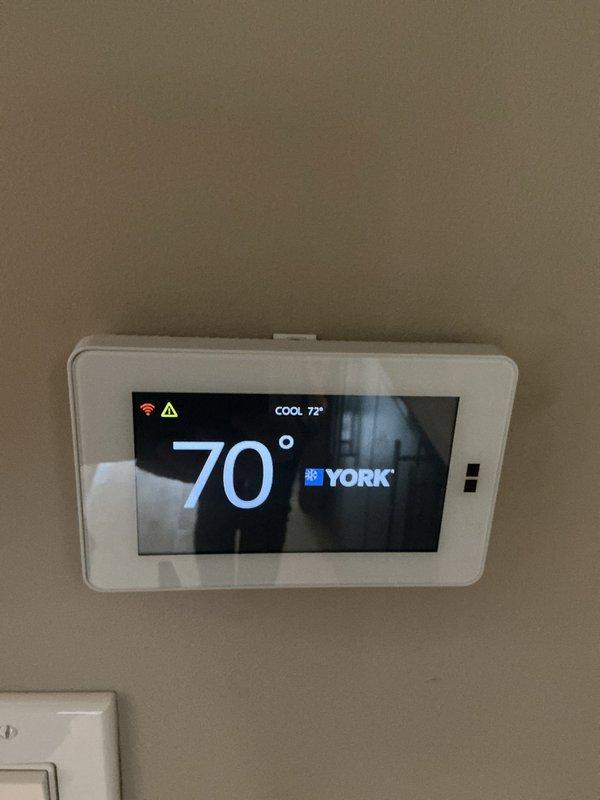 Completed scheduled heating maintenance on York HVAC system. Inspected thermostat operation showing 70°F current temperature with cooling setpoint at 72°F, verified proper display function and control responsiveness. Accessed and inspected internal components including gas valve assembly, ignition system, burner assembly with copper connections, blower motor, and all associated wiring and electrical connections; confirmed all components properly secured and functioning within normal parameters.
