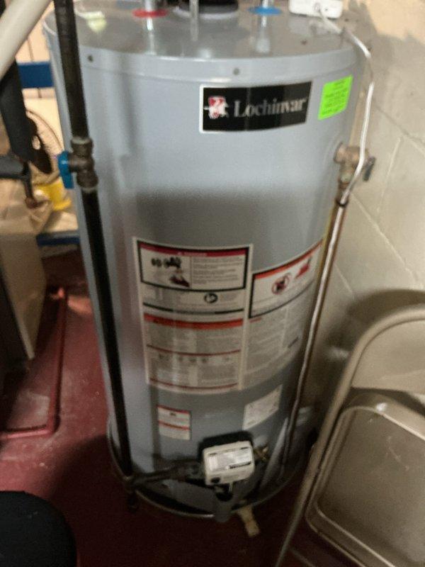 Completed comprehensive Air Care maintenance inspection on HVAC system. Verified thermostat operation with Bryant unit displaying proper temperature reading of 70 degrees and confirmed all system controls functioning correctly. Documented water heater installation and surrounding mechanical equipment showing proper installation with appropriate safety labels, pressure relief components, and plumbing connections in place.