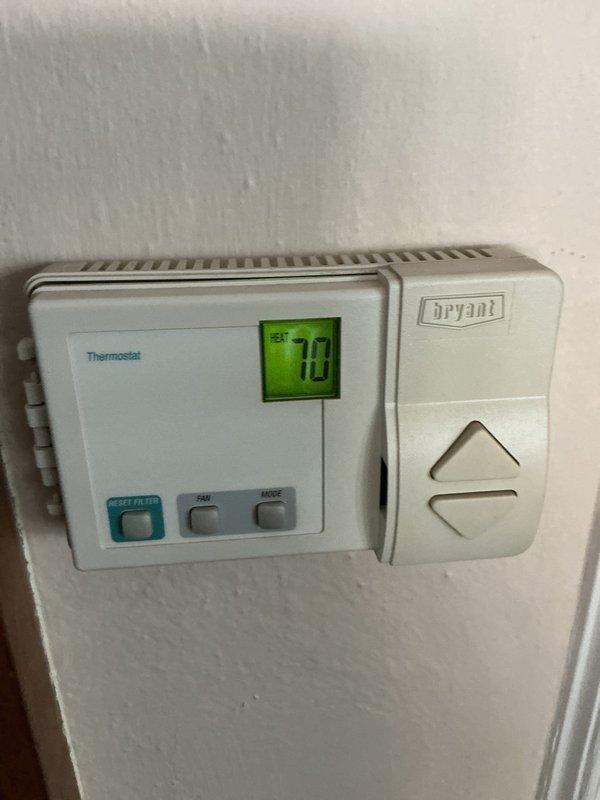 Completed comprehensive Air Care maintenance inspection on HVAC system. Verified thermostat operation with Bryant unit displaying proper temperature reading of 70 degrees and confirmed all system controls functioning correctly. Documented water heater installation and surrounding mechanical equipment showing proper installation with appropriate safety labels, pressure relief components, and plumbing connections in place.