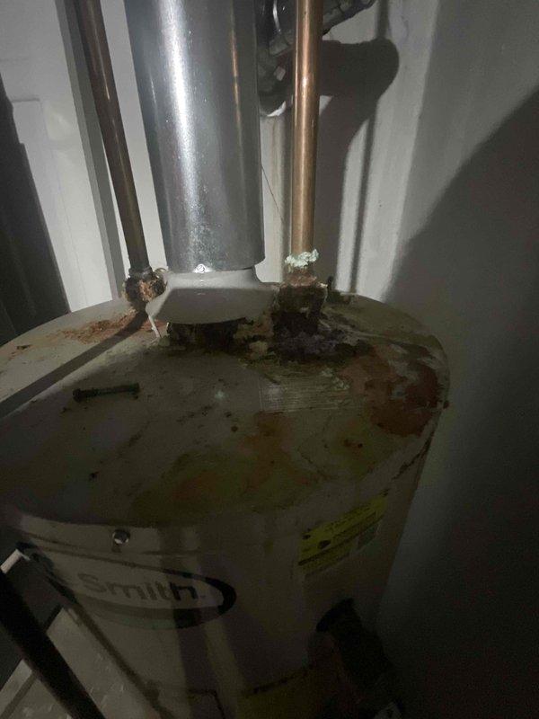 Conducted on-site assessment of gas water heater experiencing suspected leakage. Upon inspection, found extensive corrosion and rust accumulation at top pipe connections, including deteriorated copper and galvanized fittings with visible mineral deposits and water damage staining on tank surface. Water heater identified as A.O. Smith brand unit showing significant aging and lack of maintenance history, with no documented flushing performed during current occupancy period of approximately 9-10 years. Documented severe corrosion at hot and cold water inlet/outlet connections, compromised pipe threads, and rust-colored streaking indicating active or previous moisture intrusion. Photographed deteriorated conditions including corroded mounting brackets, mineral buildup around fittings, and overall tank degradation. Provided comprehensive replacement estimate for gas water heater installation due to advanced deterioration beyond economical repair.