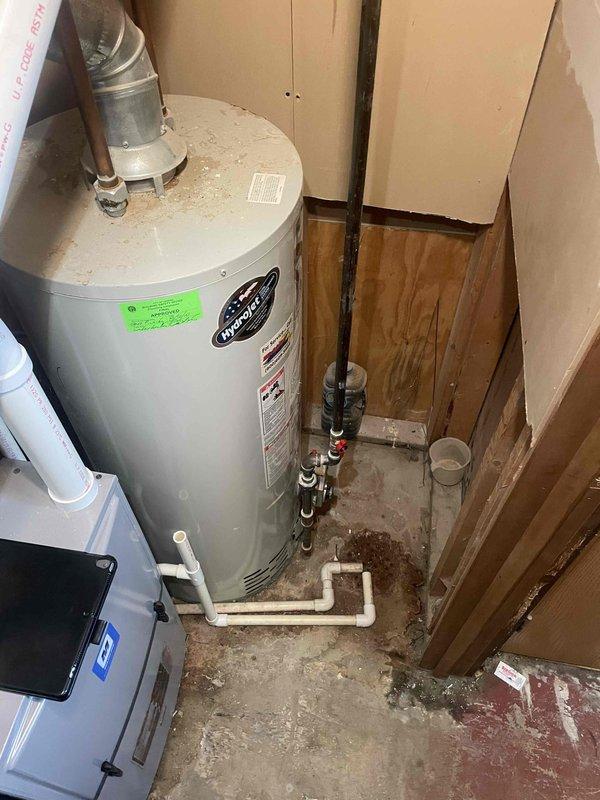 Responded to service call for malfunctioning water heater in confined utility closet space. Upon inspection, evaluated existing tanked water heater installation with inadequate clearance for proper service access and potential replacement. Unit showed signs of operational issues and was determined to be not functioning reliably. Documented current installation configuration including copper supply lines, galvanized vent piping, PVC drainage system, and shut-off valve locations. Assessed spatial constraints and determined that current clearances do not meet standard installation requirements for safe removal and replacement procedures. Provided estimate for standard tanked water heater replacement, noting that access limitations will require careful planning for equipment removal and new unit installation. Photographed existing conditions showing water heater positioning, plumbing connections, venting configuration, and available workspace dimensions for future reference during replacem
