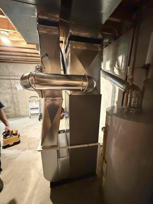Completed full HVAC system installation in residential basement including 70,000 BTU furnace, 2-ton air conditioning unit with rear discharge configuration, evaporator coil, and humidifier. Connected all ductwork to existing ventilation system, installed cylindrical vent piping, and reconnected electrical components including control panel. Mechanical permit obtained prior to installation, and all equipment positioned and secured per manufacturer specifications in utility room with proper clearances maintained.