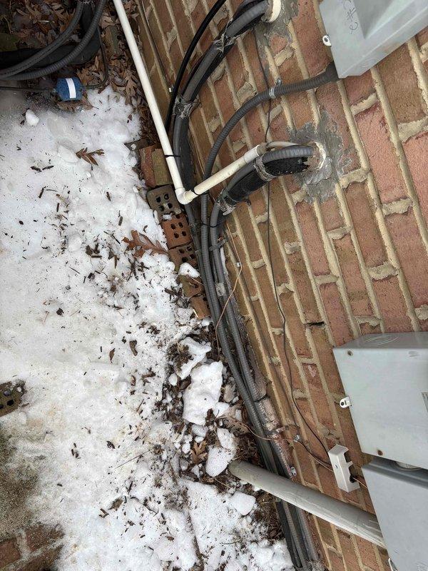 Completed electrical installation work on exterior utility connections and interior circuit breaker panel. Mounted and secured multiple electrical conduits to brick exterior wall, ensuring proper installation alongside existing PVC piping. Installed and wired new circuit breaker panel with organized wire routing and connection of multiple circuits, preparing for final inspection.