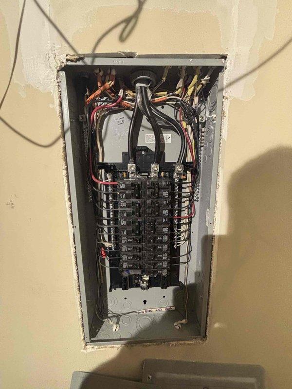 Completed electrical installation work on exterior utility connections and interior circuit breaker panel. Mounted and secured multiple electrical conduits to brick exterior wall, ensuring proper installation alongside existing PVC piping. Installed and wired new circuit breaker panel with organized wire routing and connection of multiple circuits, preparing for final inspection.