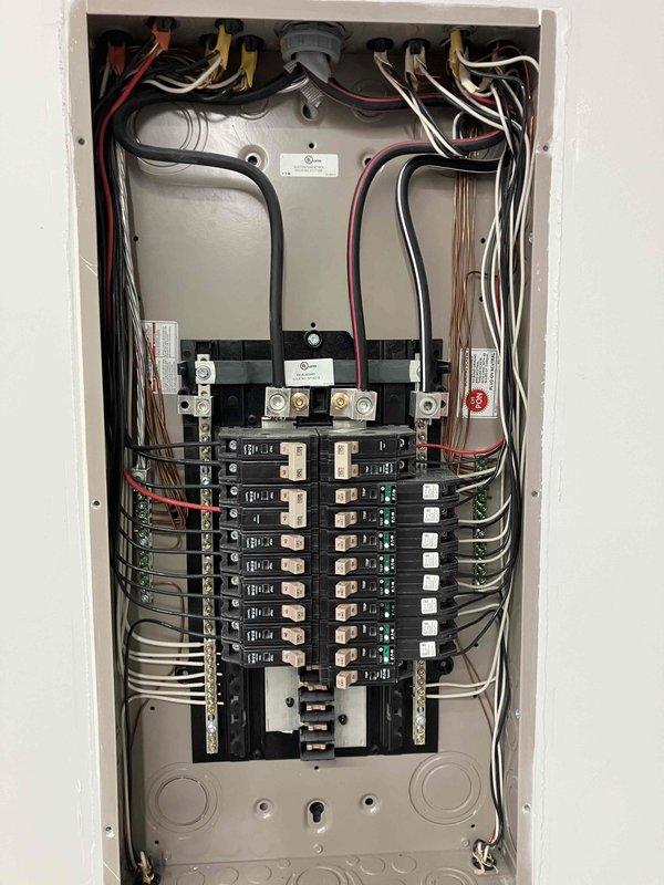 Responded to customer complaint of flickering garage lights in a 4-year-old home. Performed inspection of main electrical panel and circuit breakers. Visual examination revealed proper installation with no apparent loose connections or damaged components. Panel shows organized wiring and appears to be in normal working condition.
