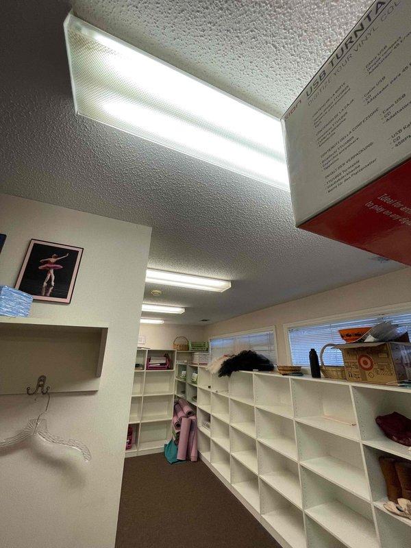 Completed conversion of 100 fluorescent light fixtures to LED across six areas: Room 1 (24), Room 2 (48), Room 3 (20), Faculty (2), Dressing Room (4), and Kitchen (2). Documented installation with photographs showing ceiling-mounted fixtures with prismatic diffusers and verified proper illumination throughout the commercial space.