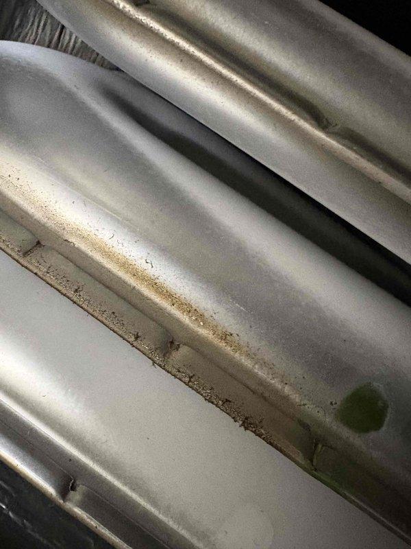 Performed second opinion inspection on suspected cracked heat exchanger. Visual inspection confirmed presence of horizontal rust line along heat exchanger seam indicating crack. Electrical diagnostics with Fluke 324 FC clamp meter showed 1.0A reading, verifying proper electrical function despite heat exchanger failure.