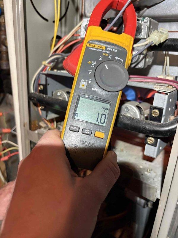 Performed second opinion inspection on suspected cracked heat exchanger. Visual inspection confirmed presence of horizontal rust line along heat exchanger seam indicating crack. Electrical diagnostics with Fluke 324 FC clamp meter showed 1.0A reading, verifying proper electrical function despite heat exchanger failure.