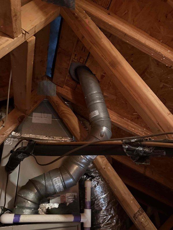 Conducted inspection of downstairs furnace reported with crack and non-operational status. Customer requested conversion from gas to electric heating system. Visual assessment of attic/crawl space revealed existing ductwork infrastructure with metal ventilation system, PVC plumbing, and electrical components integrated within wooden structural framework. Photos documented current installation conditions to support system replacement planning.