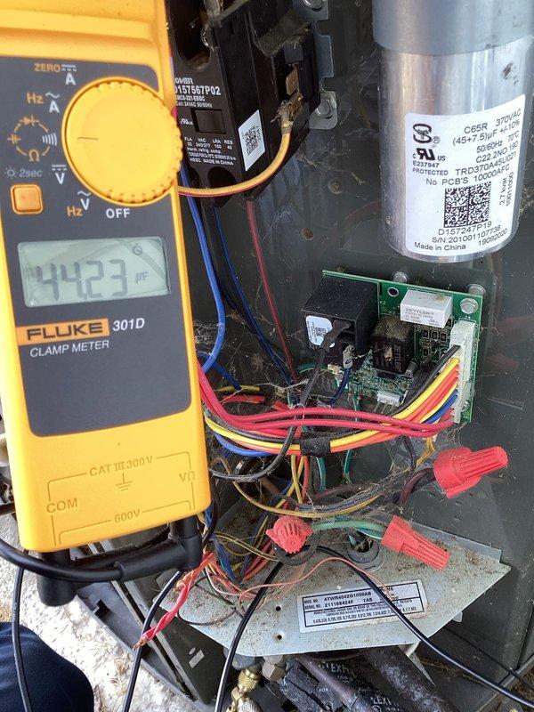 Diagnosed tripped breaker and performed electrical testing on the HVAC system using a Fluke 301D meter. Testing revealed capacitor reading of 7.181 μF, significantly below normal operating parameters, while amperage reading was 44.23, indicating electrical stress on the system. Replaced faulty capacitor, reset breaker, and verified proper system operation, restoring heat functionality.