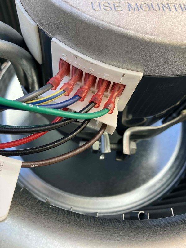 Responded to service call for non-operational thermostat and no heat. Upon inspection, found issues with the Genteq blower motor assembly in the air handler unit. Examined electrical connections at the terminal block where multiple colored wires (green, blue, red, black, and brown) connect to the motor. Documented condition with photos of the blower motor assembly and wiring connections for potential recall verification. System was restored to proper operation.
